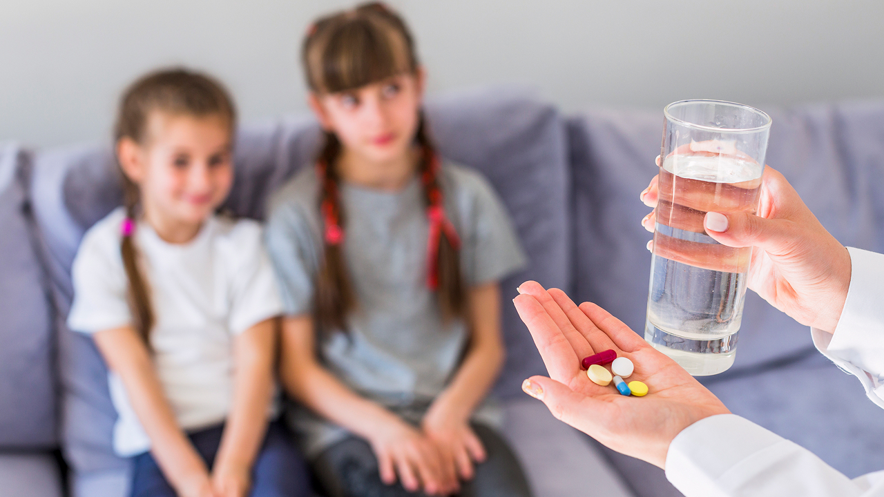 A mother is giving vitamin supplements to her kids