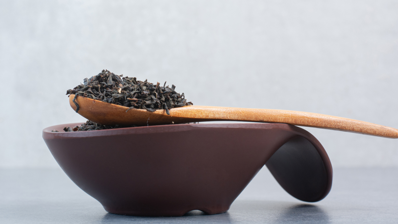 A bowl full of black seeds with a wooden spoon
