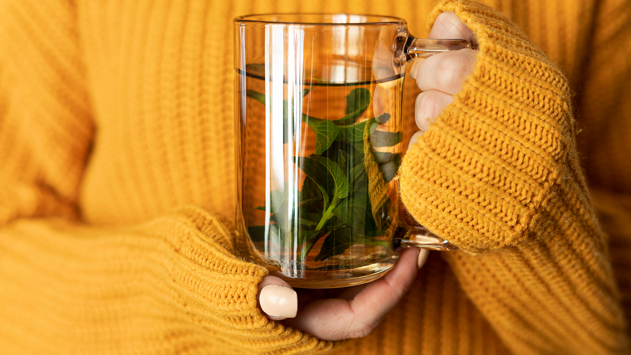 The girl is holding a cup of detox tea