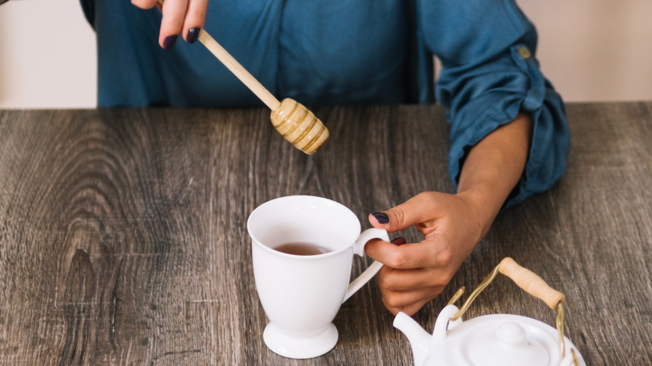 Woman adding honey to chamomile tea