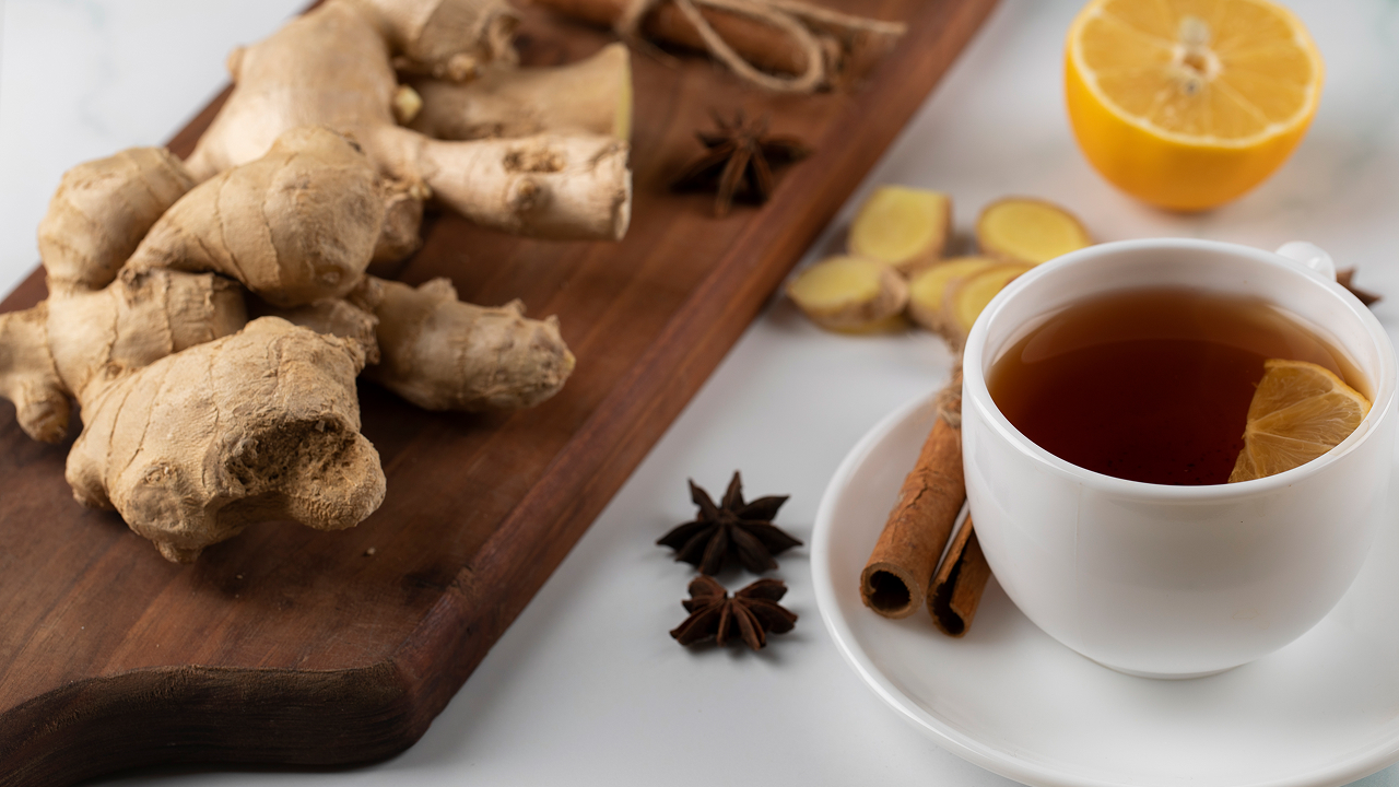A cup of tea and ginger plants on a wooden board